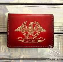 Load image into Gallery viewer, A red leather wallet featuring an engraved gold Roman eagle, laurel wreath, and SPQR emblem, displayed on a weathered wooden surface.